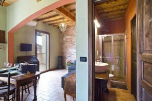 A dining area with a wooden table and chairs, a television, and a brick wall.