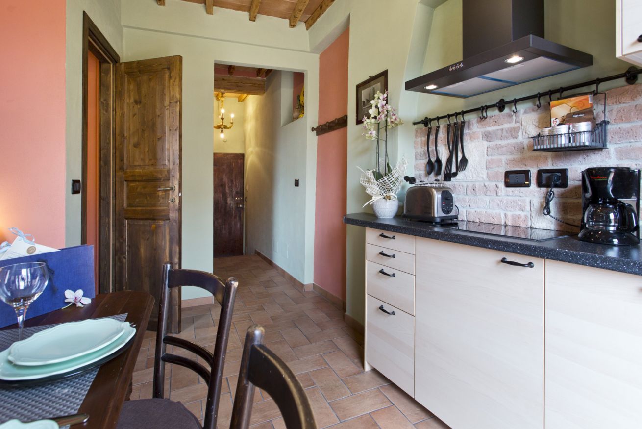 Une cuisine avec un mur en briques, des armoires en bois, un plan de travail et un porte-ustensiles suspendu.