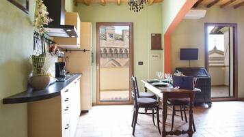 Une cuisine avec un coin repas, un plafond en bois et une vue sur un bâtiment, visible à travers une porte.