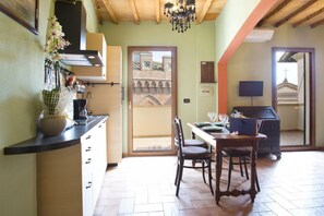 A kitchen with a dining area, wooden ceiling, and a view of a building through a door.