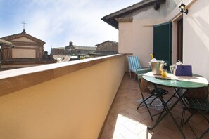 A balcony with a table, chairs, and a view of buildings in the background.