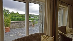 A room with a sliding glass door leading to a balcony with a stone wall and potted plants.