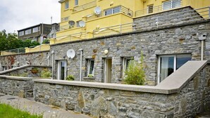 A stone building with a flat roof, multiple windows, and a small balcony.