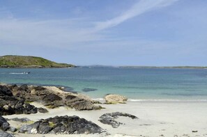 A beach with rocky foreground, calm water, and a distant hill. - Apartment 263 - Clifden - sleeps 5 guests  in 3 bedrooms (Clifden)