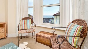 A cozy room with wicker chairs and a wooden bench, a small wooden table, and a view of the sea through large windows. - The Salt Pot -  a cottage that sleep 6 guests  in 3 bedrooms (Ventnor)