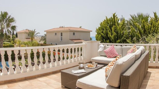 A balcony with a sofa, a table, and a potted plant. - Villa Casa Mia by Ezoria Villas (Coral Bay)