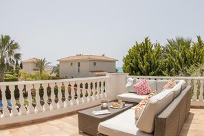 Un balcon avec un canapé, une table et un pot de fleurs.