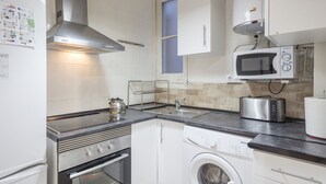 Een kleine keuken met een fornuis, magnetron, broodrooster en wasmachine.