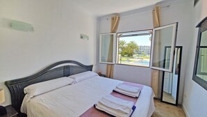 A hotel room with a bed, a window with curtains, and a view of the outside. - Villa Charlie - Denia, Costa Blanca (Denia)