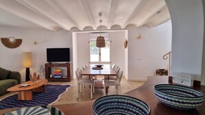 A living room with a sofa, coffee table, TV, and dining area with chairs and a table. - Villa Charlie - Denia, Costa Blanca (Denia)