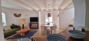 A living room with a sofa, coffee table, TV, and dining area with chairs and a table. - Villa Charlie - Denia, Costa Blanca (Denia)