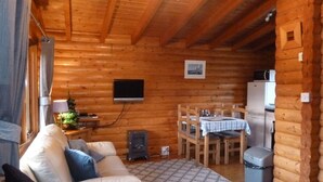 A cozy log cabin interior with a sofa, a dining table, and a television.