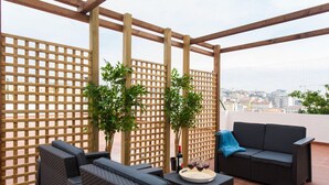 A rooftop terrace with wicker furniture, a sofa, and potted plants. - JOIVY Stunning apt near Avenida da Liberdade (Lisboa)