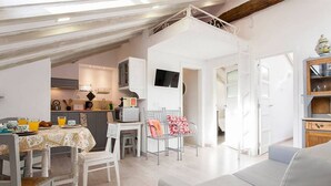 A spacious living area with a dining table set for breakfast, a sofa, and a kitchen in the background.