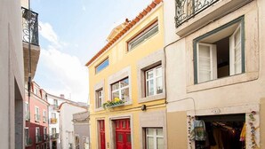 A narrow street with buildings featuring red doors and balconies.
