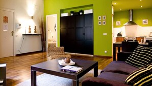 Ein Wohnzimmer mit Holzboden, einer Couch, einem Couchtisch und einer Küchenzeile mit Herd und Schränken.