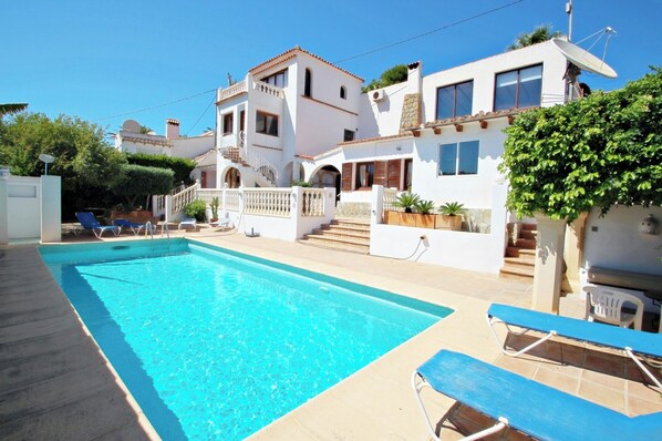 A swimming pool with lounge chairs, a white building with balconies, and a satellite dish. - Tanja - modern, well-equipped villa with private pool in Costa Blanca (Benissa)