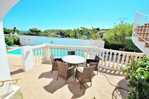 A patio with a round table and wicker chairs, overlooking a swimming pool and lush greenery. - Tanja - modern, well-equipped villa with private pool in Costa Blanca (Benissa)