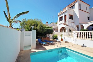 A pool area with blue lounge chairs, a white building with a balcony, and a clear blue sky. - Tanja - modern, well-equipped villa with private pool in Costa Blanca (Benissa)
