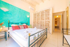 A bed with a metal frame, a teal wall, and a wooden door.