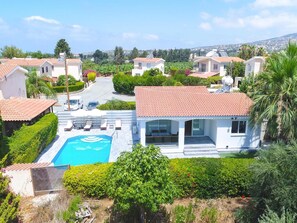 Zona residencial com piscina, casas com telhados vermelhos e vegetação exuberante.