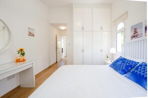 Quarto com uma cama grande, cômoda, espelho e guarda-roupa.