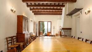 A spacious dining area with a long wooden table and chairs, wooden beams on the ceiling, and a view through a doorway. - Casale Santa Francesca - Country Villa with swimming pool in Orcia Valley, Tuscany (Campiglia D'orcia)