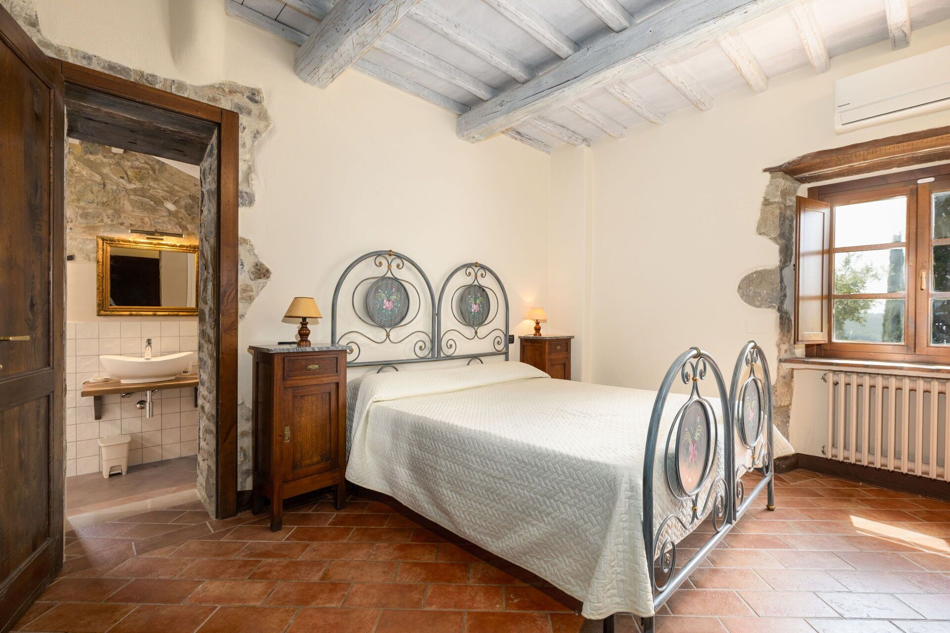 A bedroom with a bed, a nightstand, a dresser, a mirror, and a window.