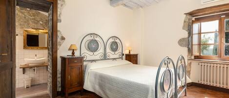 A bedroom with a bed, a nightstand, a dresser, a mirror, and a window.