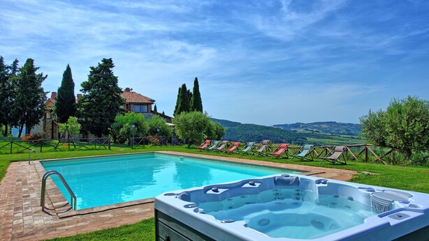 A swimming pool with a hot tub, surrounded by a grassy area and trees, with a view of hills in the background. - Casale Santa Francesca - Country Villa with swimming pool in Orcia Valley, Tuscany (Campiglia D'orcia)