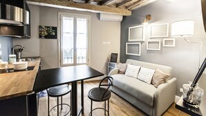 Een moderne keuken met een houten aanrecht, een zwarte eettafel en een grijze bank.