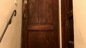 Een houten deur met een metalen handgreep en een metalen grendel.