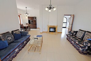 Una sala de estar con dos sofás, una mesa de centro, una chimenea, una estantería y un comedor.