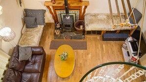 Un salon chaleureux avec une cheminée, un canapé, une table basse et un fauteuil suspendu.