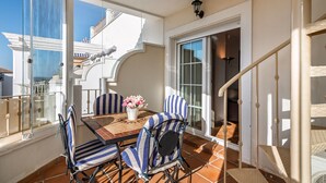 A balcony with a table, chairs, and a vase of flowers. - Las Dunas - Punta del Moral Beach PLHD145P118 (Punta del Moral)