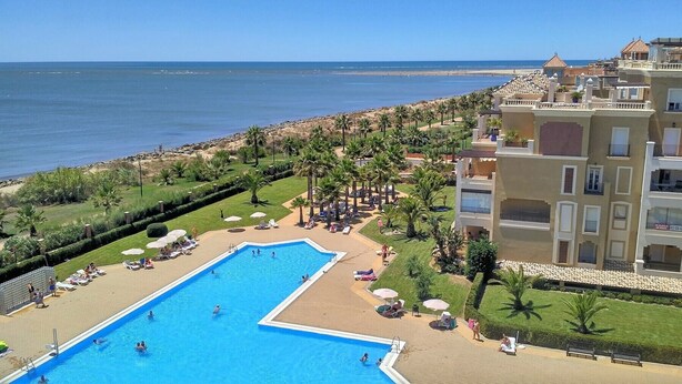 Ein Resort mit Pool, Palmen und Meerblick.