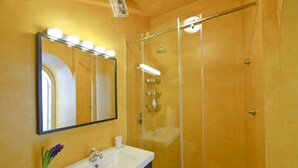 A bathroom with a glass-enclosed shower, a vanity with a sink, and a mirror with lights. - Casale Fralisa - Marvelous terrace and hot tub with sea view (Praiano)
