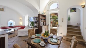 A spacious living area with a dining table set for four, a comfortable seating area with a sofa, and a staircase leading to an outdoor area. - Casale Fralisa - Marvelous terrace and hot tub with sea view (Praiano)