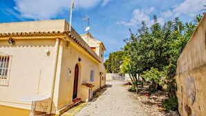 A narrow alleyway with a building on the left, a small table, and a tree-lined path. - Linea - sea view villa with private pool in Teulada (Teulada)