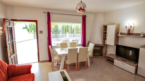 A living room with a dining table, chairs, a sofa, a TV, and a fireplace. - Linea - sea view villa with private pool in Teulada (Teulada)