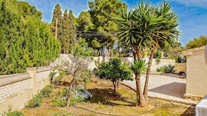 A garden with various trees and shrubs, a white fence, and a paved area. - Linea - sea view villa with private pool in Teulada (Teulada)