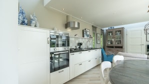 A modern kitchen with white cabinetry, stainless steel appliances, and a dining area with a round table and chairs.