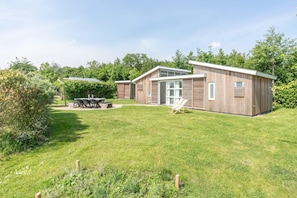 Une maison moderne en bois dotée d’un patio, d’un coin repas et d’un espace extérieur aménagé et abrité.