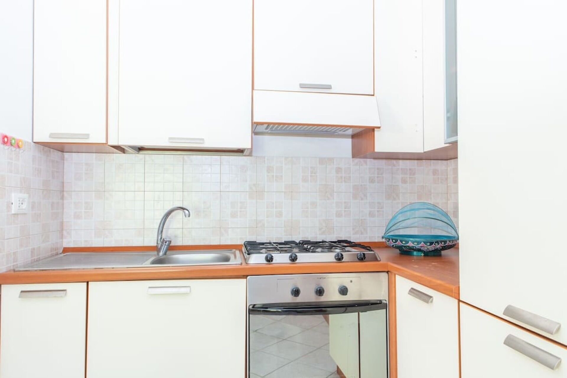 Une cuisine avec des meubles blancs, un évier en acier inoxydable, une cuisinière à gaz et un lave-vaisselle.