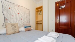A bedroom with a bed, pillows, a wooden wardrobe, and a door.