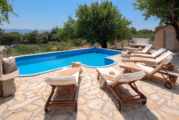 A swimming pool with lounge chairs and a stone patio.