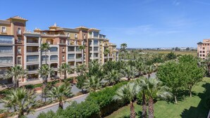 Um hotel com vários andares e varandas, rodeado por palmeiras e vegetação.