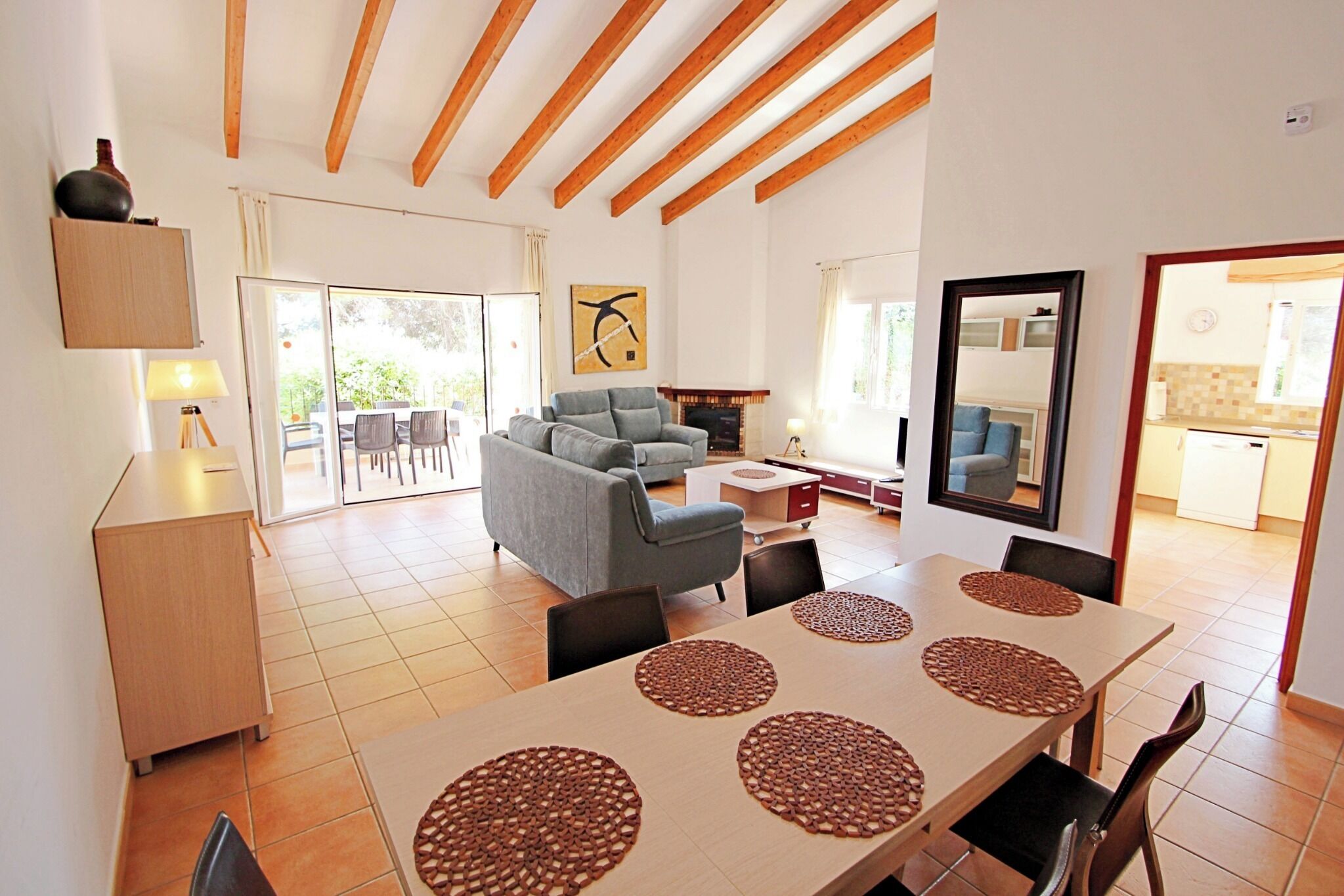 Amplia sala de estar con sofá, mesa de comedor con individuales y chimenea.