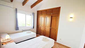 Camera da letto con due letti, una finestra con tende, un termosifone, armadi in legno e una lampada a parete.