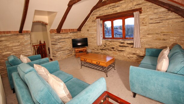 A cozy living room with stone walls, wooden beams, and blue sofas.